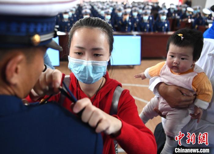 新消防員楊振的妻子彭莉與女兒現(xiàn)場見證丈夫加入“火焰藍(lán)”的神圣時刻?！⒅铱?攝